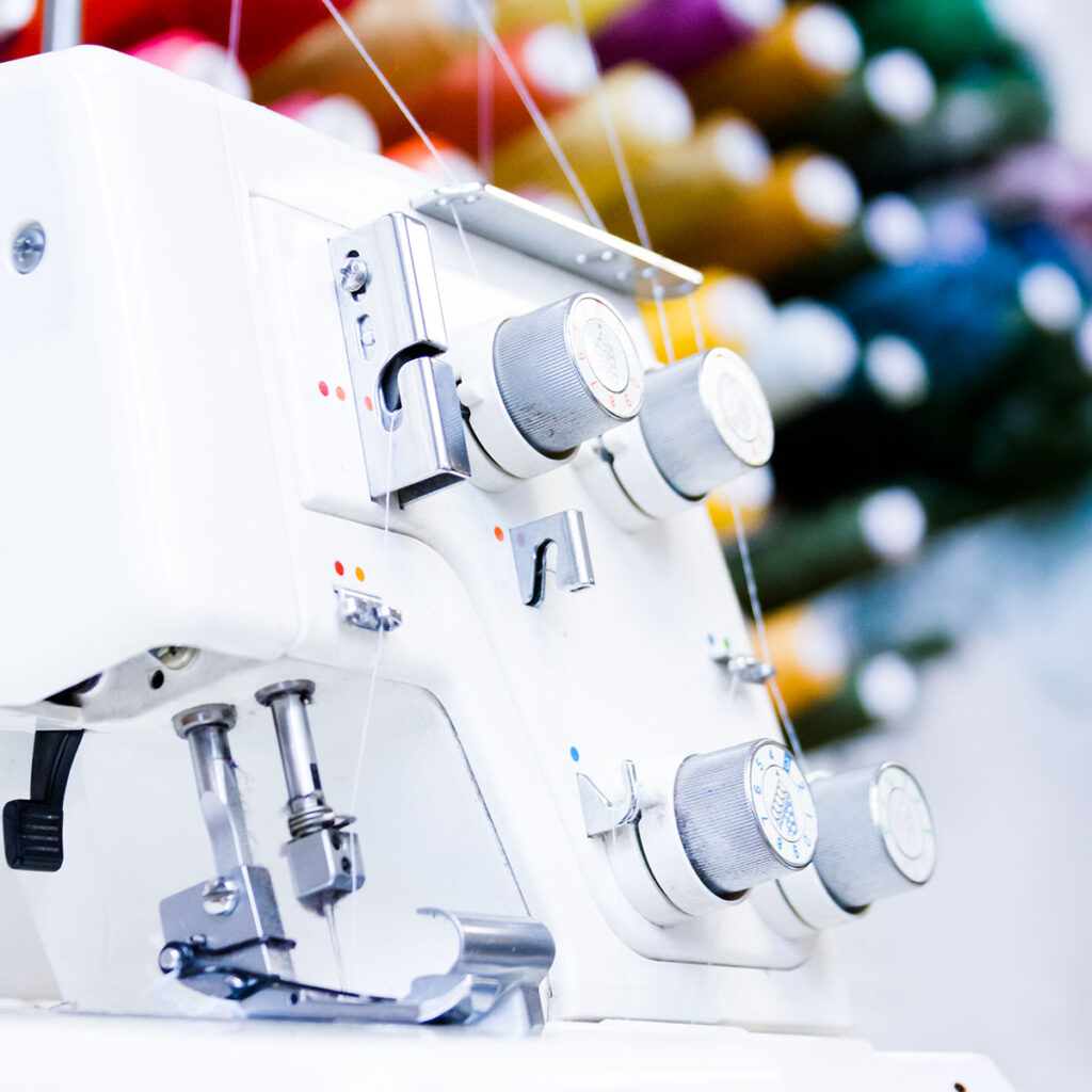 Overlock Nähmaschine vor bunten Garnen
