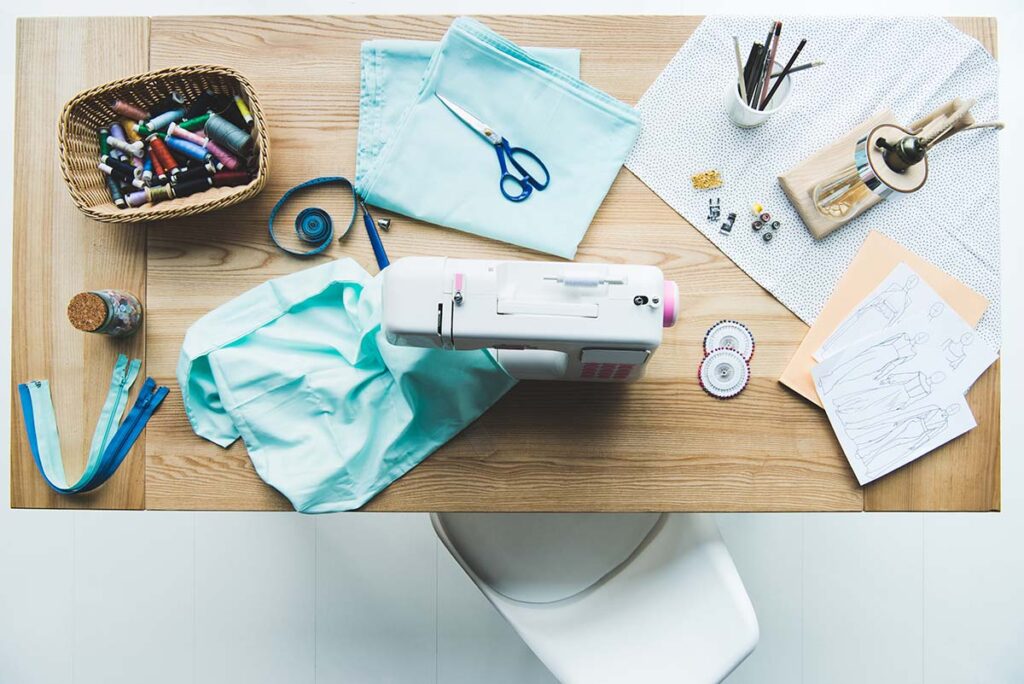Aufgeräumte Flatlay-Nähecke mit Nähmaschine und Mintstoff